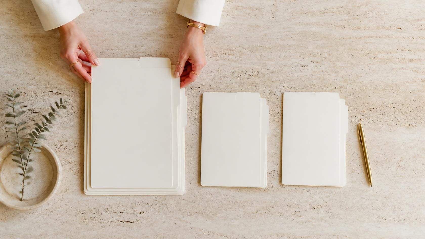 Hands sorting document folders into three groups on a travertine surface