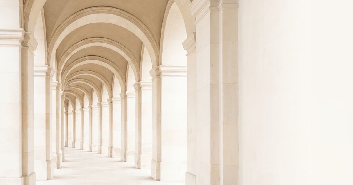 A bright stone colonnade where repeating columns carry the structure above them